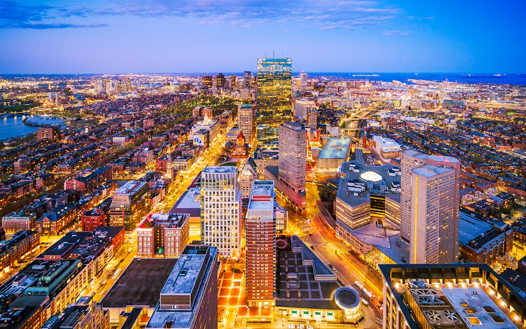 Nighttime cityscape view from Prudential Tower, Boston, with illuminated streets and buildings.