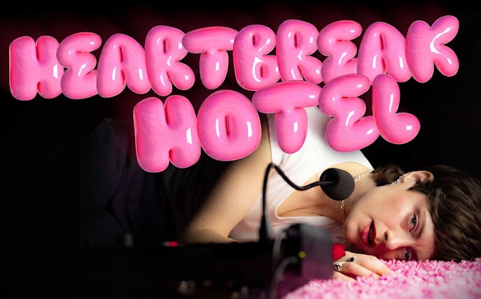 Person lying on pink carpet with microphone, "Heartbreak Hotel" in bold pink letters above.