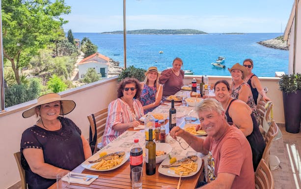 Group dining on terrace with sea view during Blue Cave and Blue Lagoon boat tour.