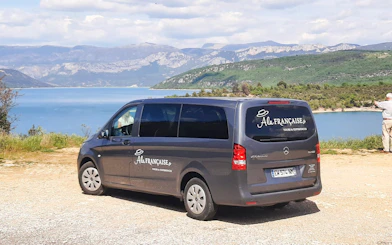 Tour van parked near Pont de Galetas with scenic lake and mountain view in the background.