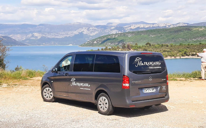 Tour van parked near Pont de Galetas with scenic lake and mountain view in the background.