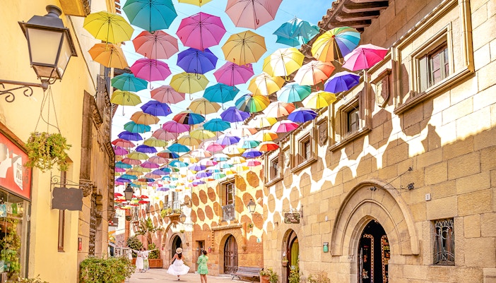 Tourists exploring Poble Espanyol, Barcelona, admiring unique architecture and vibrant streets.