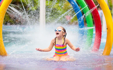 Child playing under colorful fountain in Aqualand children's area.