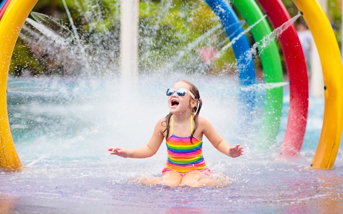 Child playing under colorful fountain in Aqualand children's area.