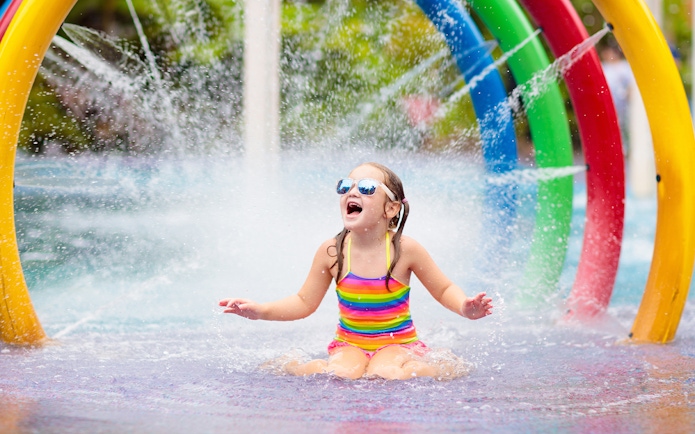 Child playing under colorful fountain in Aqualand children's area.