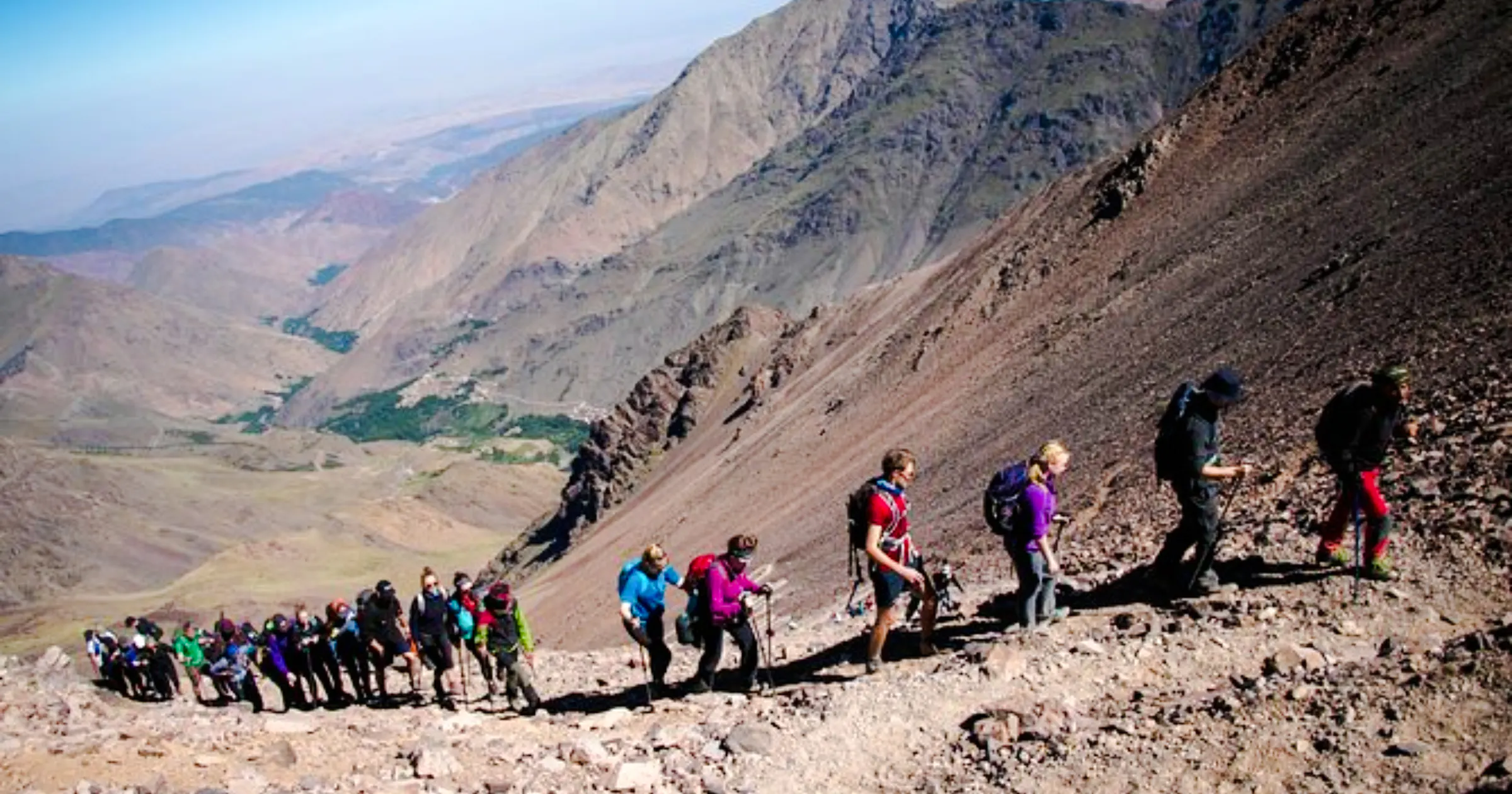 Hikers ascending rocky trail in Marrakesh mountains.