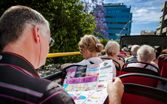 Tourists reading a route map on a Santa Cruz hop-on hop-off bus.