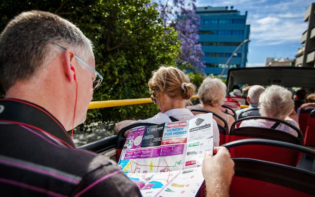 Tourists reading a route map on a Santa Cruz hop-on hop-off bus.