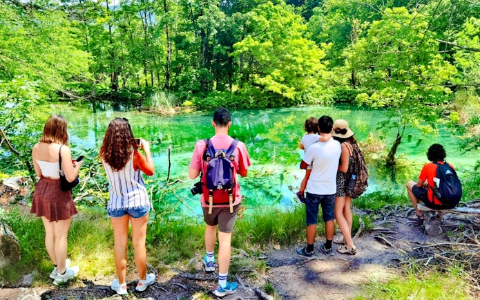Visitors enjoying the scenic view of Plitvice Lakes National Park's vibrant green waters.