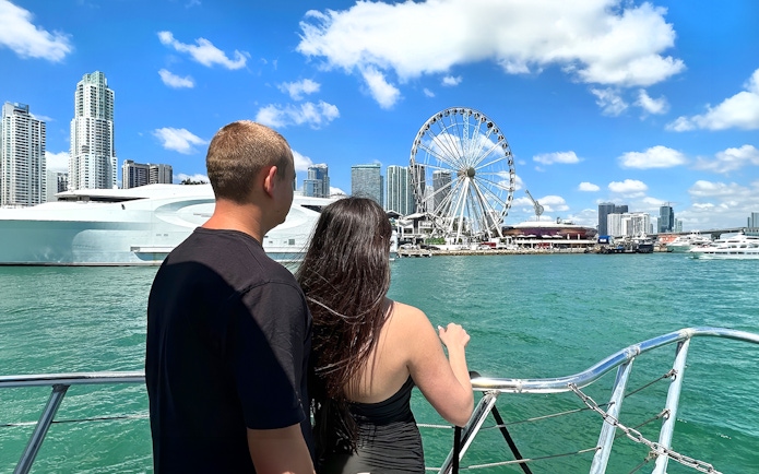 Couple on boat with Miami skyline and Ferris wheel in view.