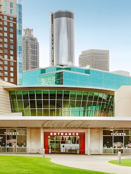 Entrance to the World of Coca-Cola in Atlanta with city skyline in background.