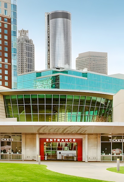 Entrance to the World of Coca-Cola in Atlanta with city skyline in background.