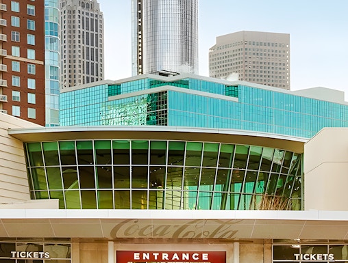 Entrance to the World of Coca-Cola in Atlanta with city skyline in background.