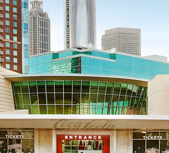 Entrance to the World of Coca-Cola in Atlanta with city skyline in background.