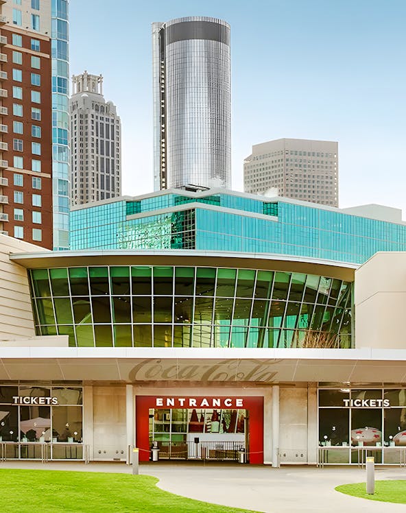 Entrance to the World of Coca-Cola in Atlanta with city skyline in background.
