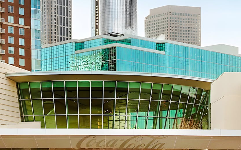 Entrance to the World of Coca-Cola in Atlanta with city skyline in background.