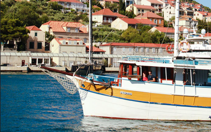 Boat docked at Dubrovnik port with hillside houses in background during Blue Cave Swim Stop tour.
