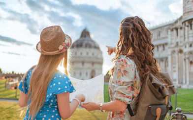 Tour guide explaining Pisa Baptistery to a girl holding a map in Pisa, Italy.