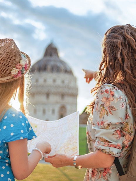 Tour guide explaining Pisa Baptistery to a girl holding a map in Pisa, Italy.