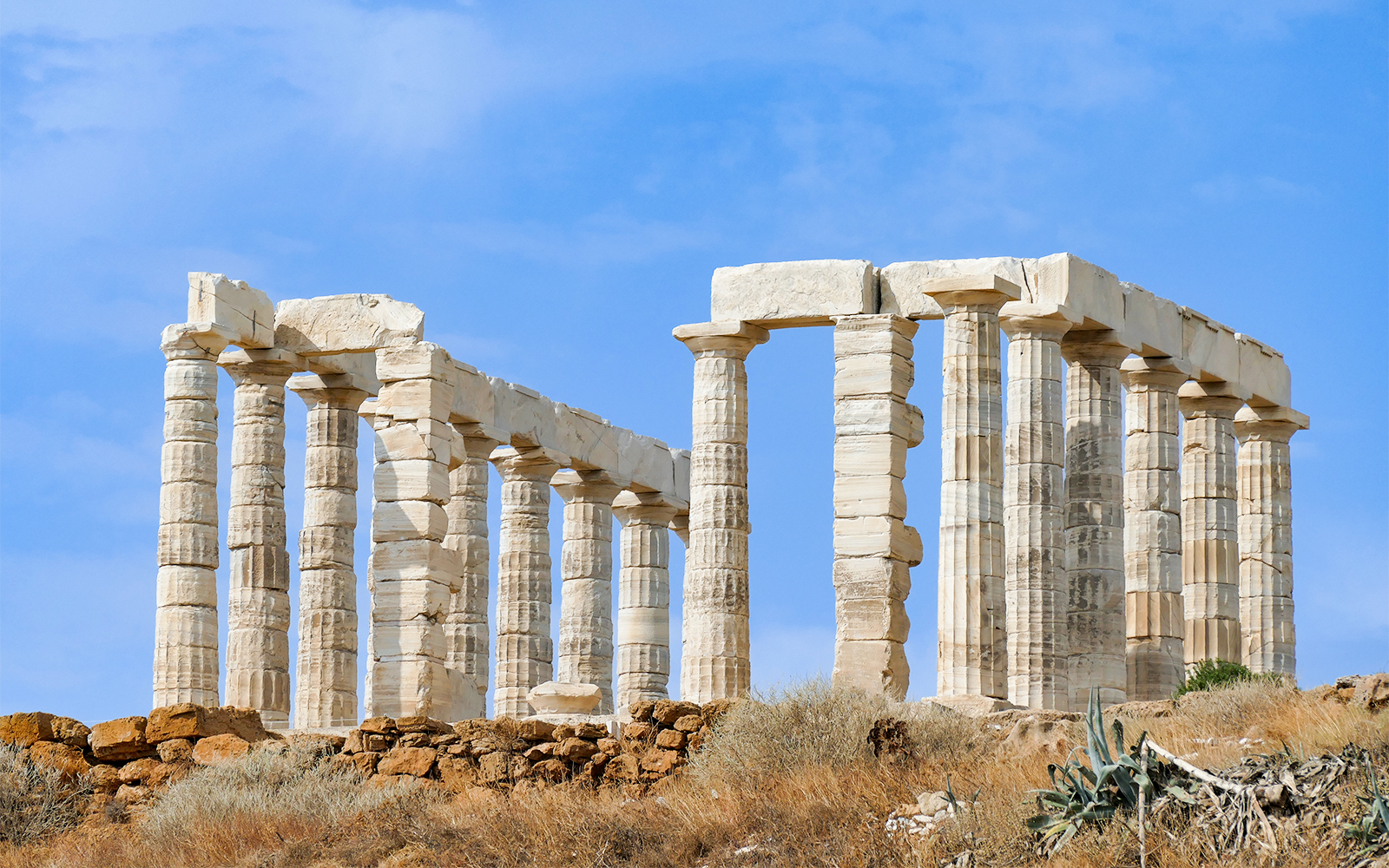 Temple of Poseidon ruins at Cape Sounio, Greece, under a clear blue sky.