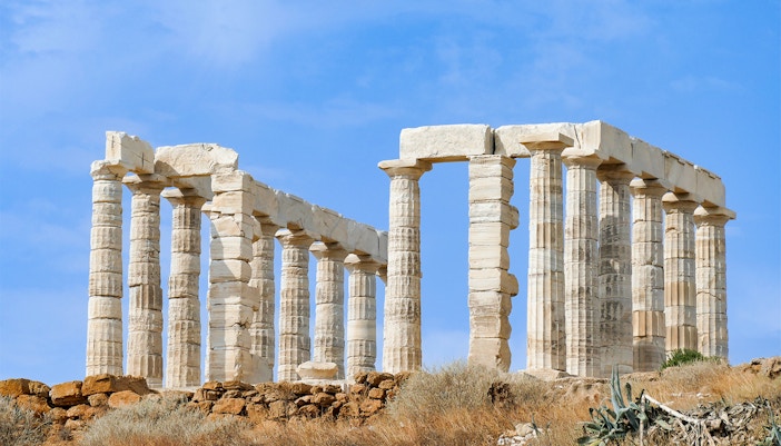 Temple of Poseidon ruins at Cape Sounio, Greece, under a clear blue sky.
