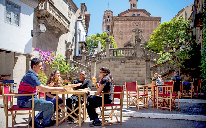Visitors enjoying a meal at an outdoor cafe in Poble Espanyol, Barcelona.
