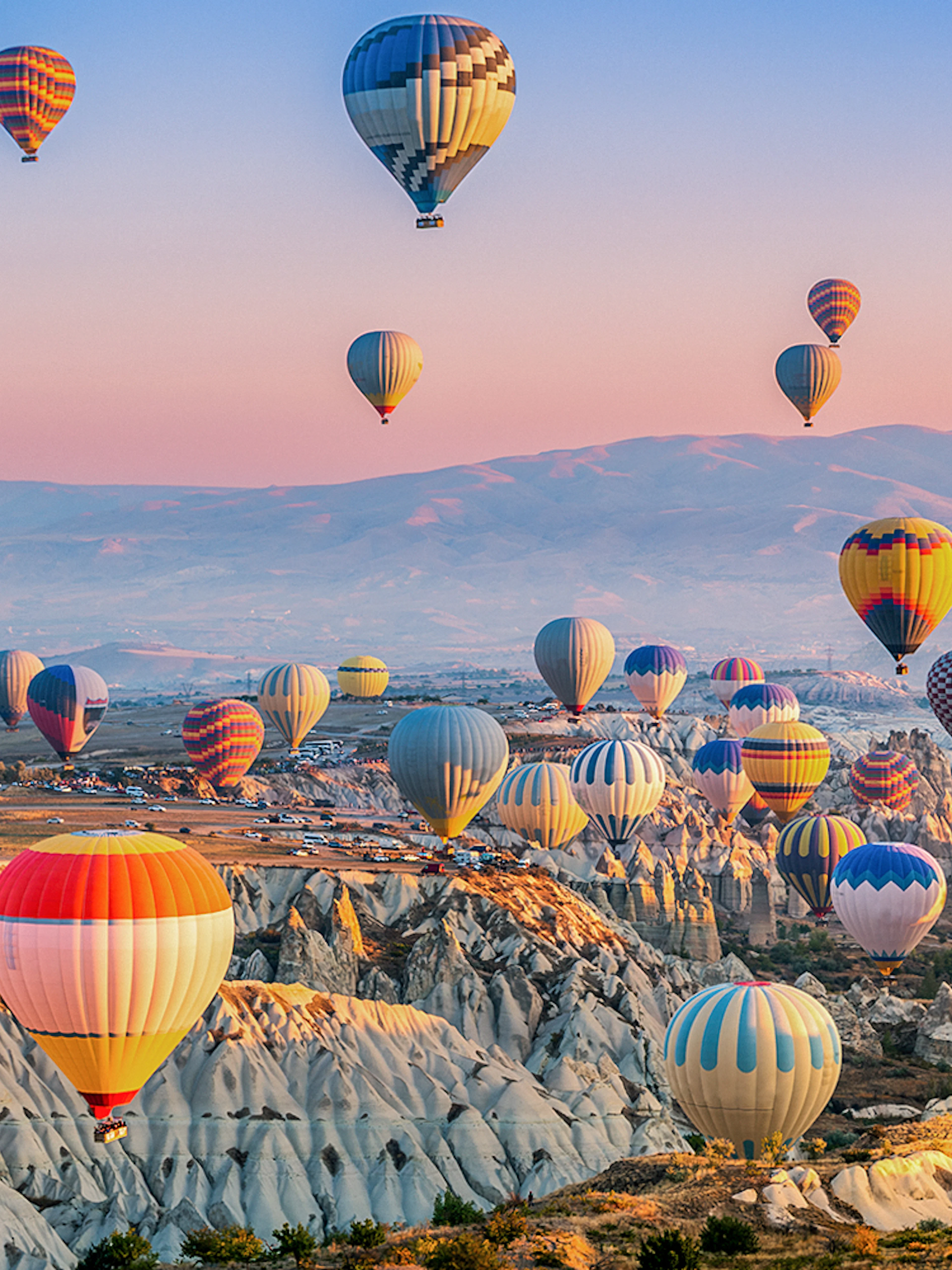 Hot air balloons over Göreme's unique rock formations in Cappadocia at sunrise.