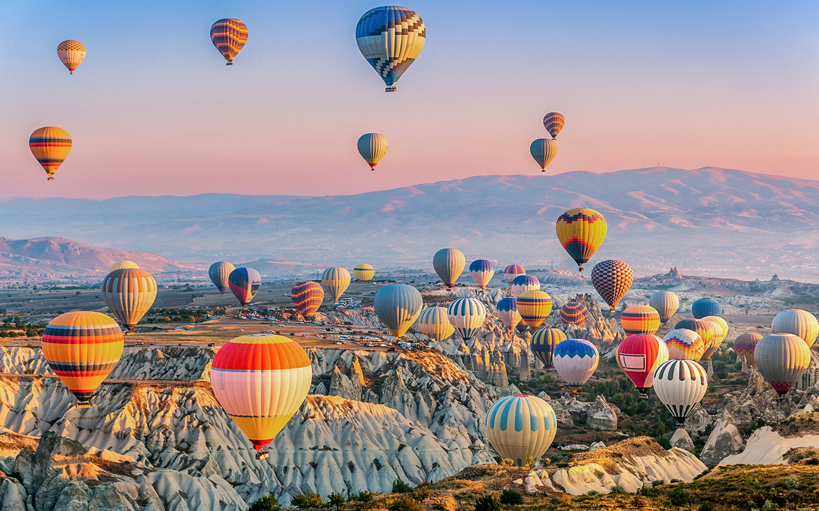Hot air balloons over Göreme's unique rock formations in Cappadocia at sunrise.