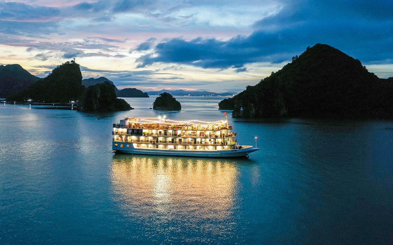 Emotion Night Cruise ship sailing through Halong Bay with limestone karsts in the background.