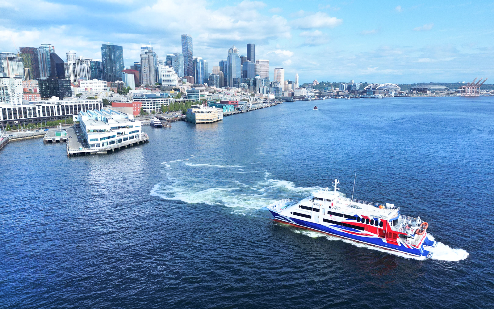 High-speed ferry on Puget Sound with Seattle skyline in the background.