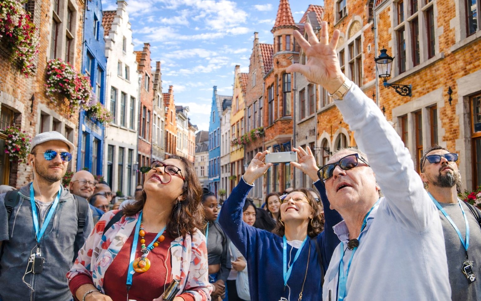 Tourists on a guided walking tour in Bruges, admiring historic architecture.