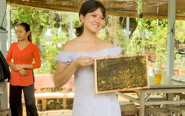 Woman holding a honeycomb frame during Mekong Delta Day Tour from Ho Chi Minh.