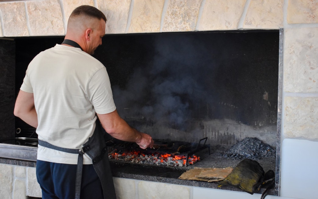 Man grilling food over open flames during Blue Lagoon and 3 Island tour from Split.