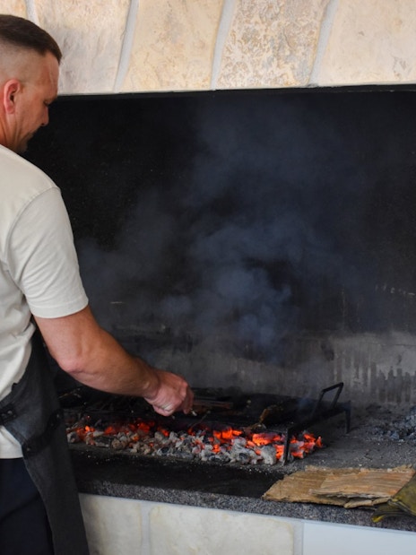 Man grilling food over open flames during Blue Lagoon and 3 Island tour from Split.