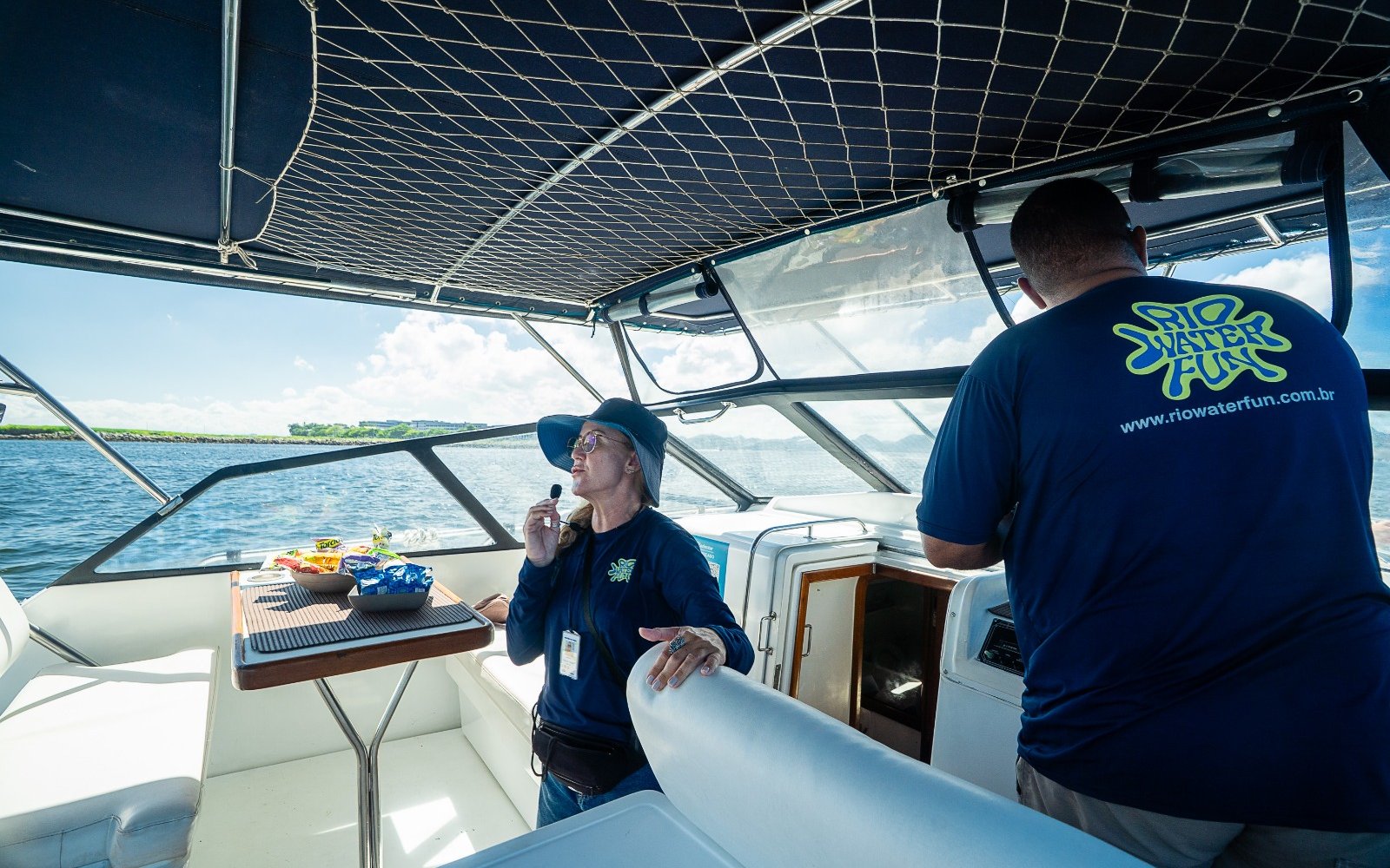 Boat guide explaining sightseeing spots to tourists during Rio boat tour.