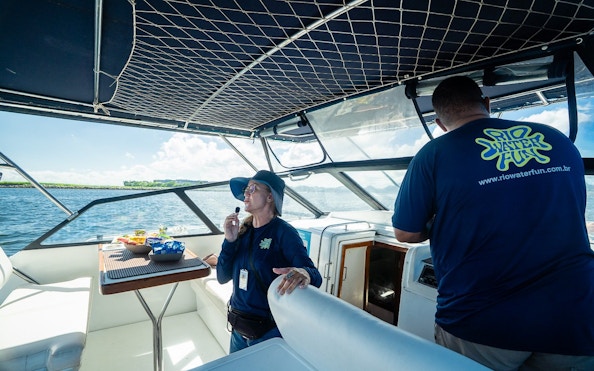 Boat guide explaining sightseeing spots to tourists during Rio boat tour.