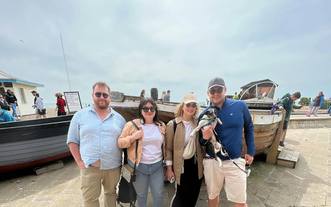 Group of people with a dog in front of a boat on Brighton beach during a self-guided city exploration game.