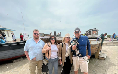 Group of people with a dog in front of a boat on Brighton beach during a self-guided city exploration game.
