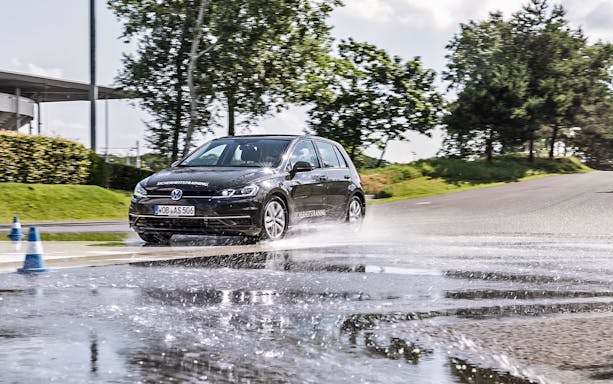 Car navigating wet track at Autostadt Theme Park, Wolfsburg.