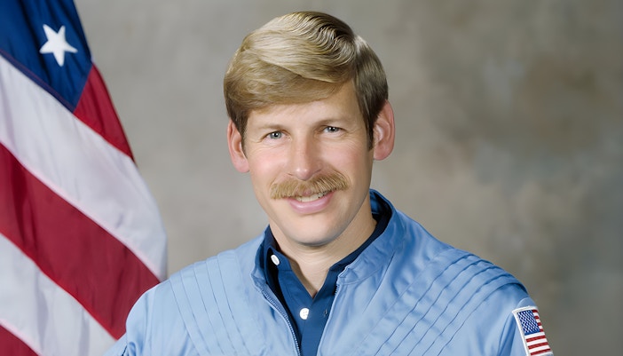Astronaut Woody Spring in space suit with Earth in the background.