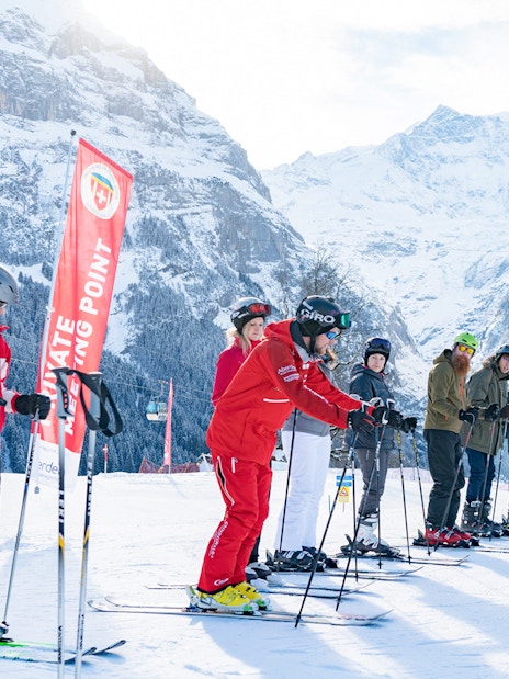 Group of skiers in Grindelwald with instructor, snowy mountains in background.