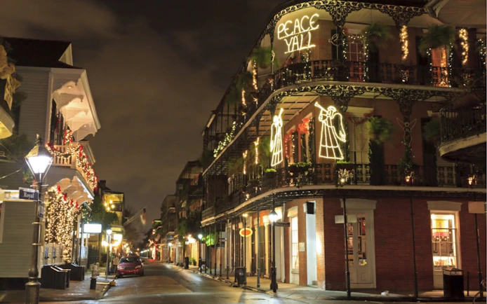 New Orleans street at night with festive lights and historic architecture.