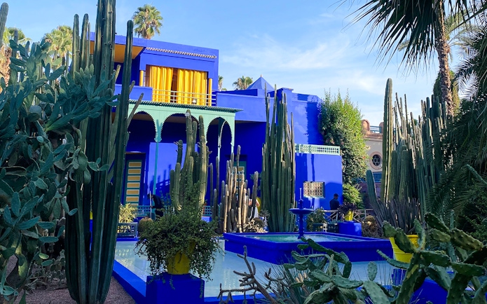 Jardin Majorelle's vibrant blue villa surrounded by tall cacti and lush greenery.