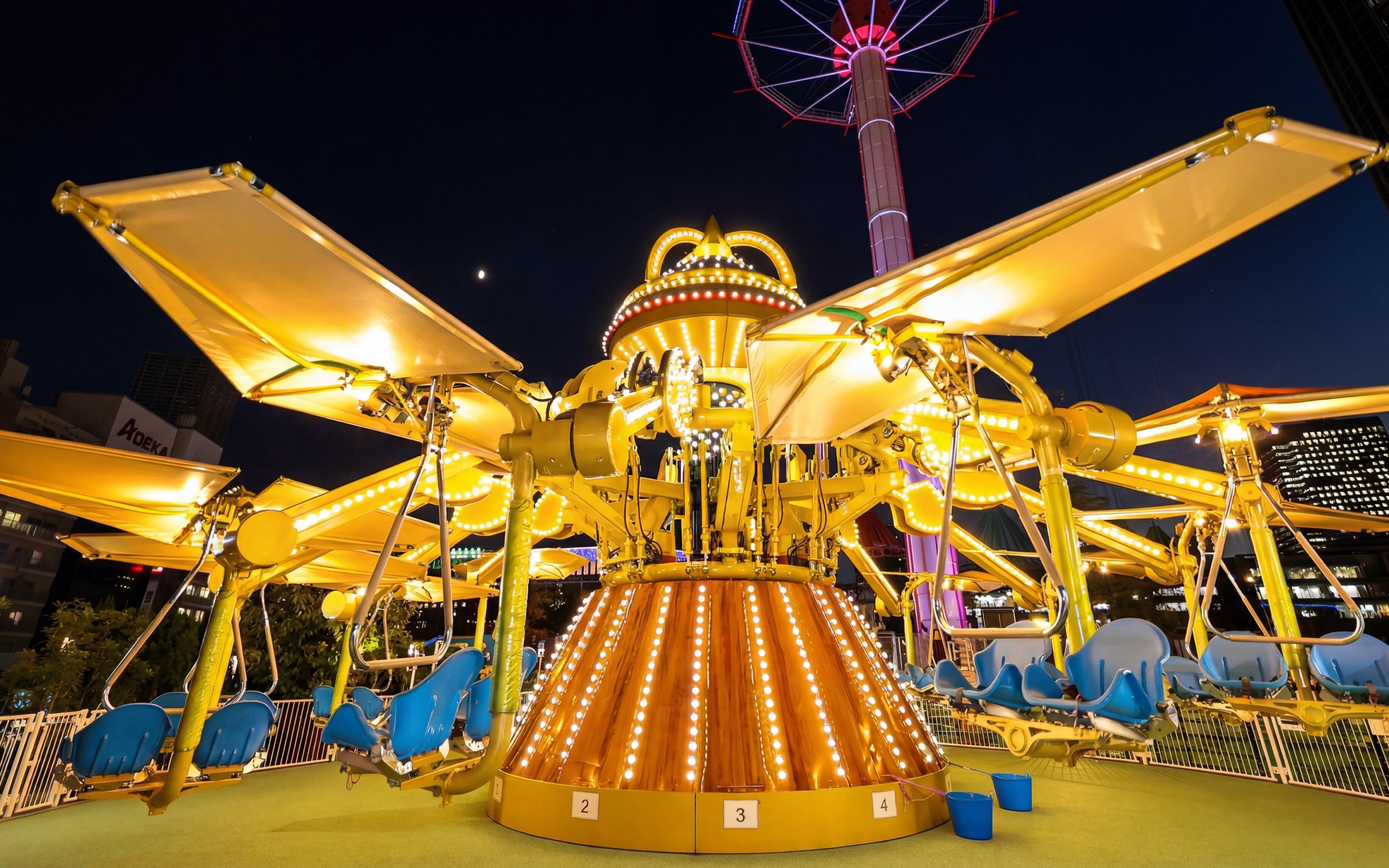 Amusement ride at night near Tokyo Dome with illuminated seats and structure.