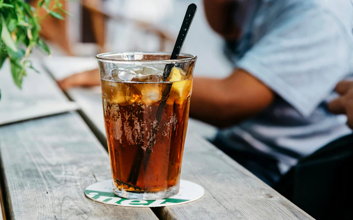 Refreshing glass of cola with ice on a wooden table.