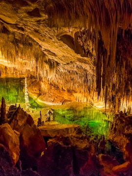Stalactites and stalagmites inside Drach Caves, Mallorca, with colorful lighting.