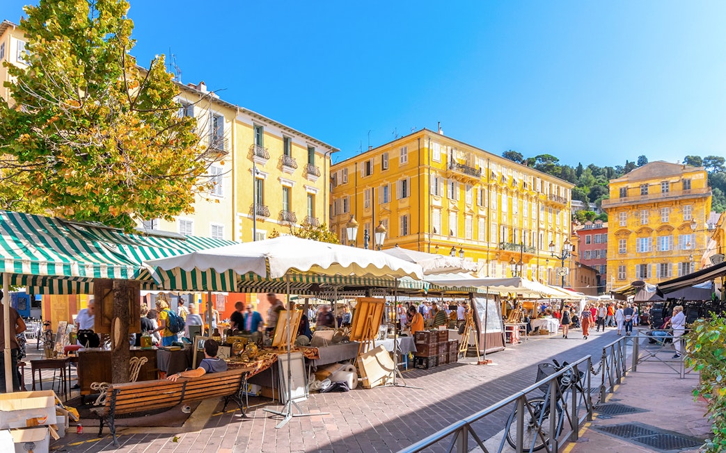Cours Saleya Flower Market with stalls and yellow buildings in Nice, France.