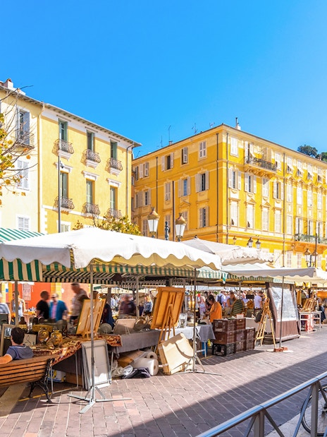 Cours Saleya Flower Market with stalls and yellow buildings in Nice, France.