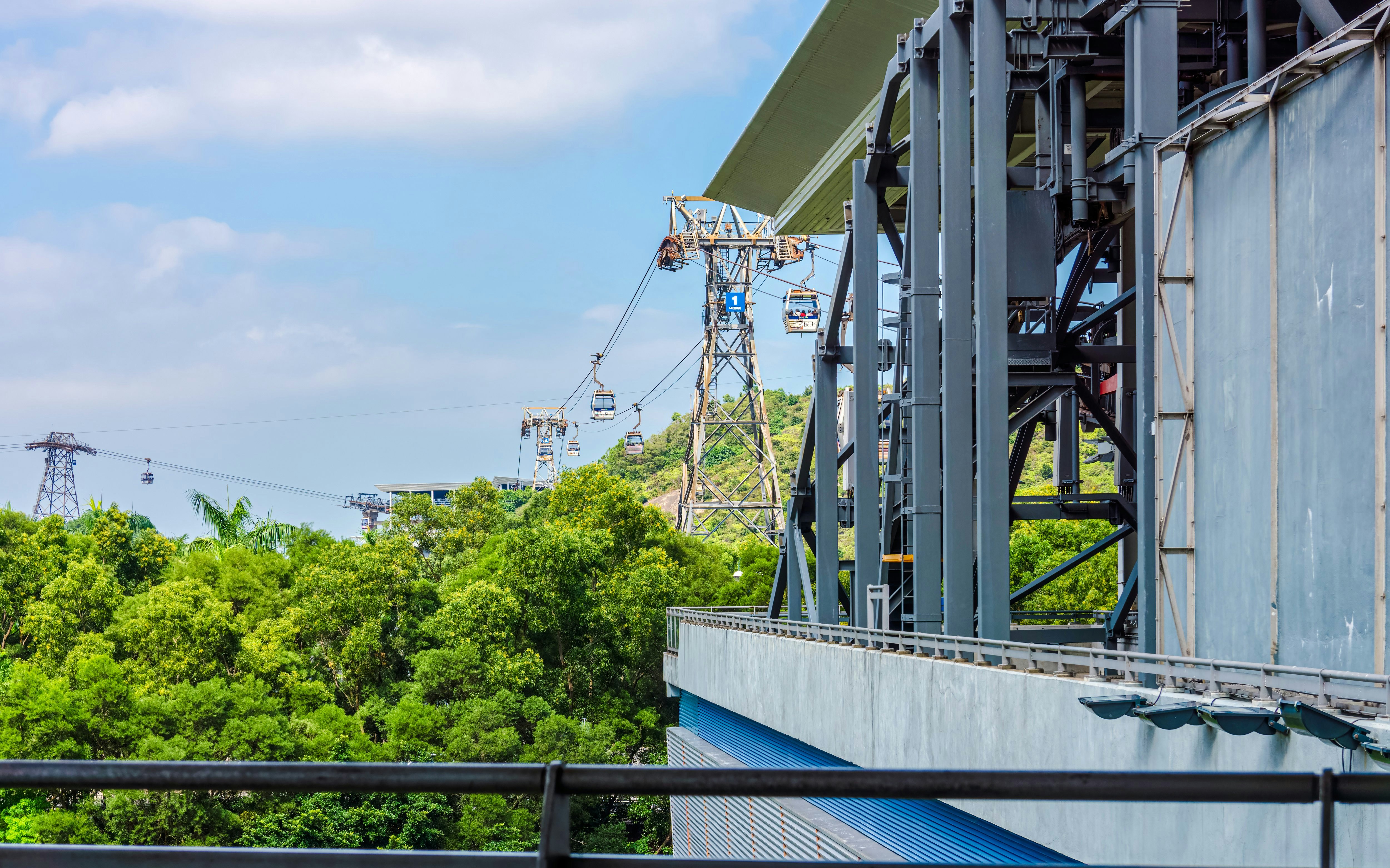 Side view of Ngong Ping bi-cable gondola lift base station with lush greenery.