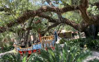 Colorful pirate ship under oak trees in New Orleans park, part of self-guided city exploration game.